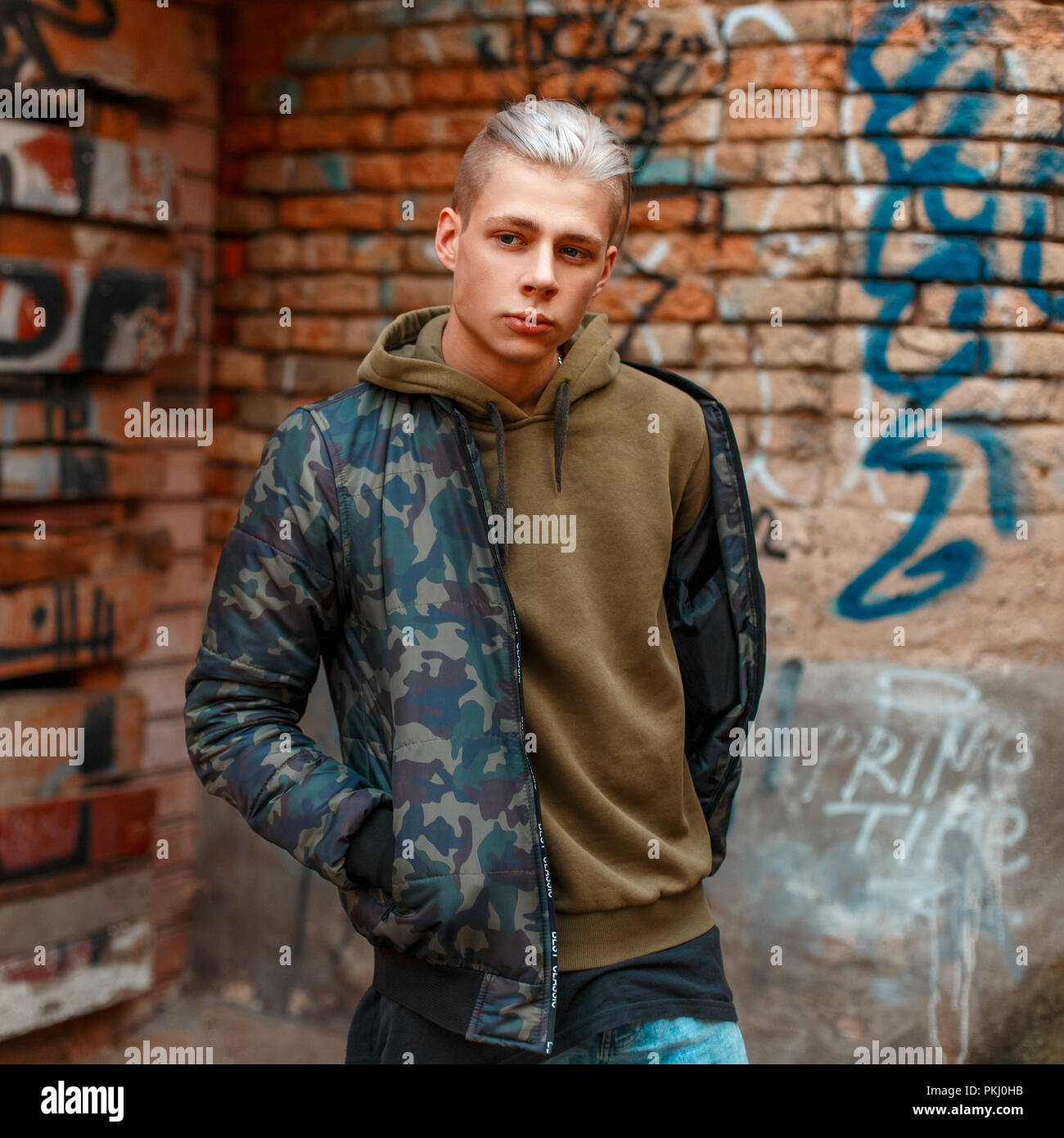 Giovane uomo elegante militare nella moda vicino a una parete Foto Stock