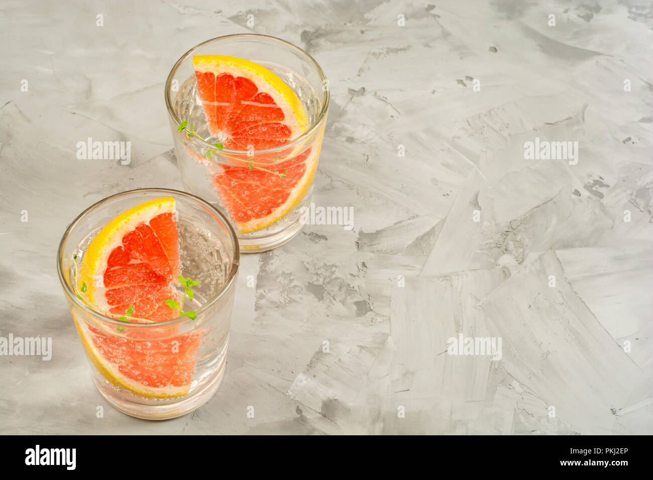 Pompelmo limonata. Due bicchieri di detox bere acqua con succo di pompelmo, rametti di rosmarino e il ghiaccio. Concetto di ricetta, cocktail Foto Stock