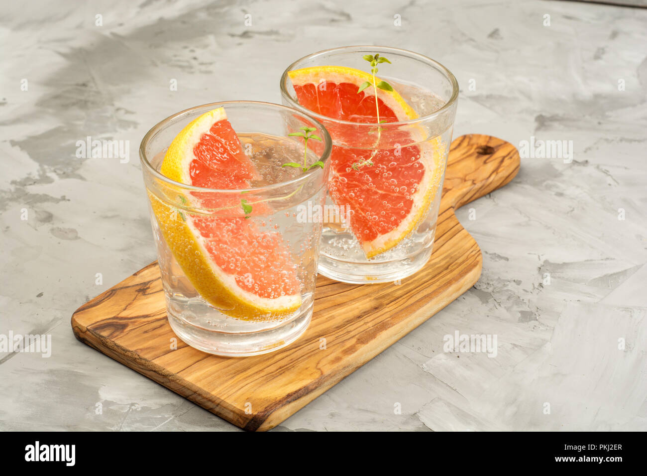 Pompelmo limonata. Due bicchieri di detox bere acqua con succo di pompelmo, rametti di rosmarino e il ghiaccio. Concetto di ricetta, cocktail Foto Stock