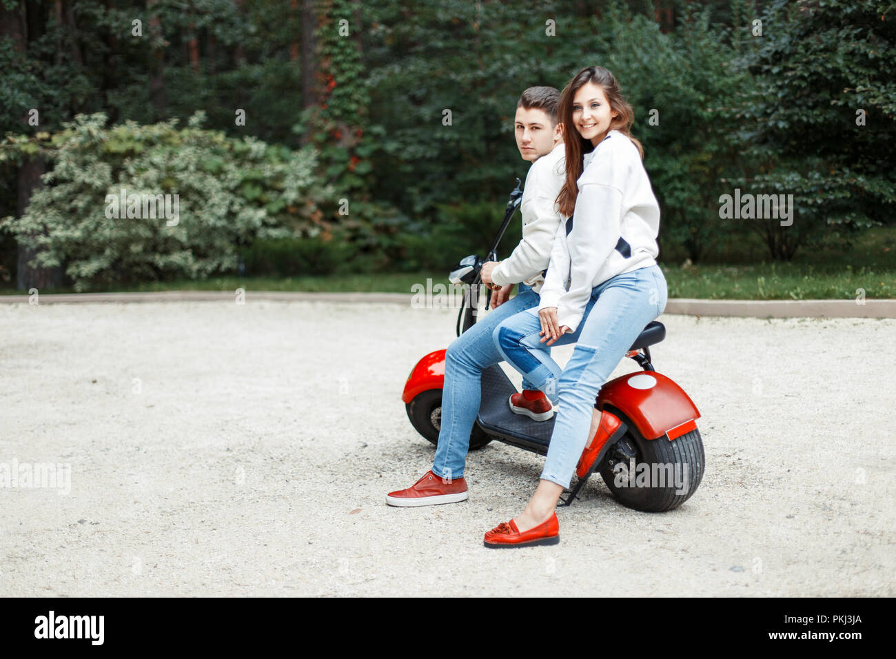 Giovane bella giovane nella marca di abbigliamento elegante con una bicicletta elettrica Foto Stock