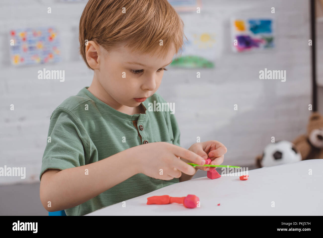 Ragazzo focalizzato con colorati di plastilina scolpire la figura a tavola in camera Foto Stock