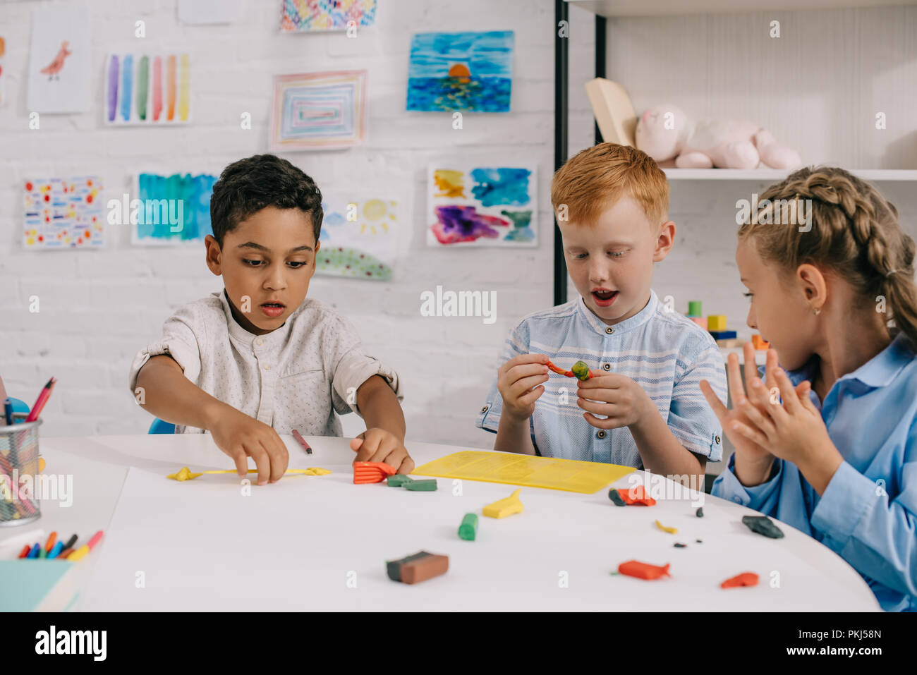 Ritratto di carino multietnica i bambini in età prescolare scolpire figure di plastilina in aula Foto Stock