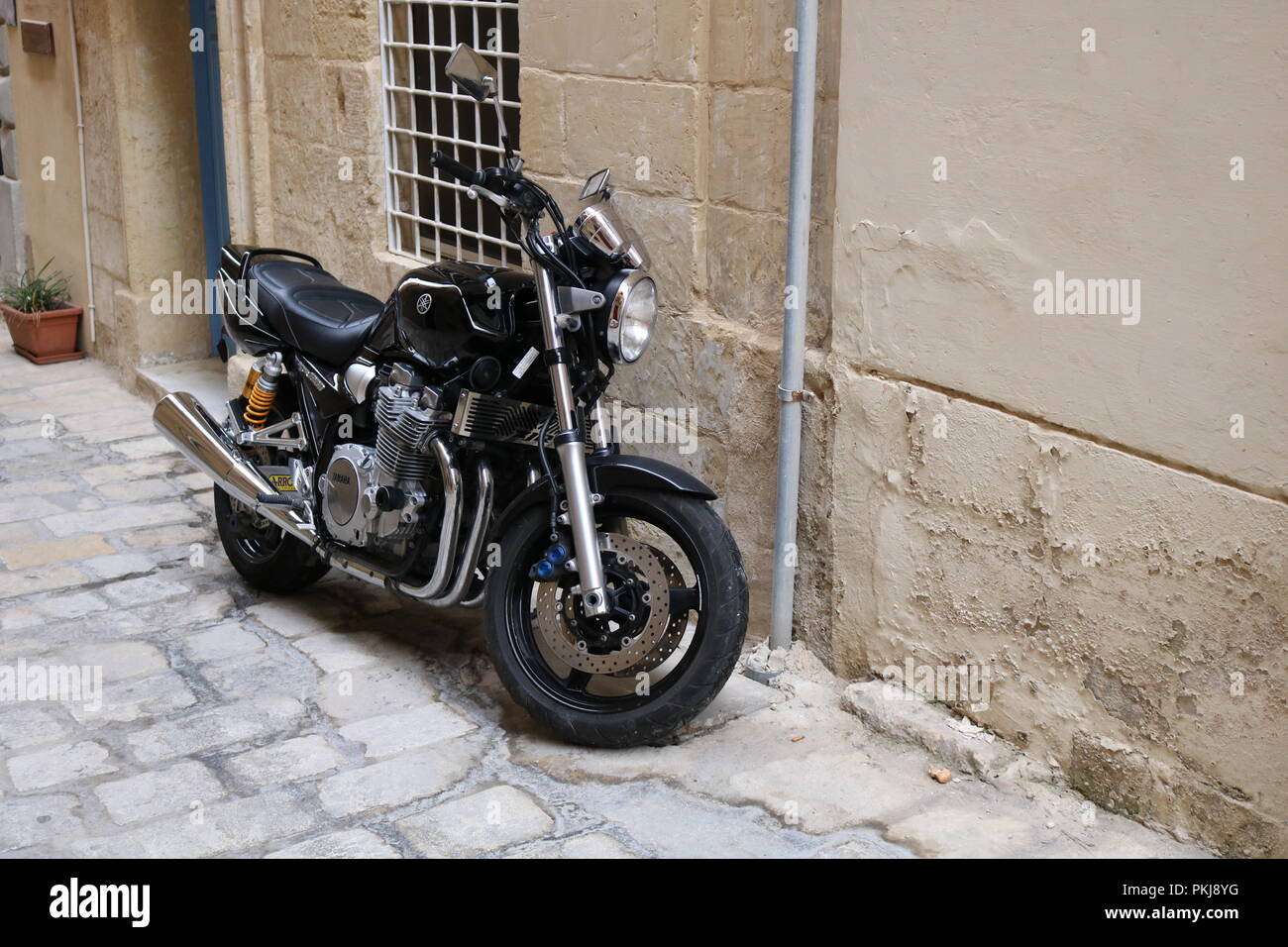Un motociclo nero parcheggiato su strade di Malta Foto Stock