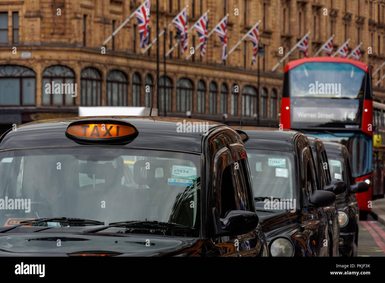 Taxi neri su Brompton Road a Knightsbridge con il grande magazzino Harrods in background, Londra Inghilterra Regno Unito Regno Unito Foto Stock