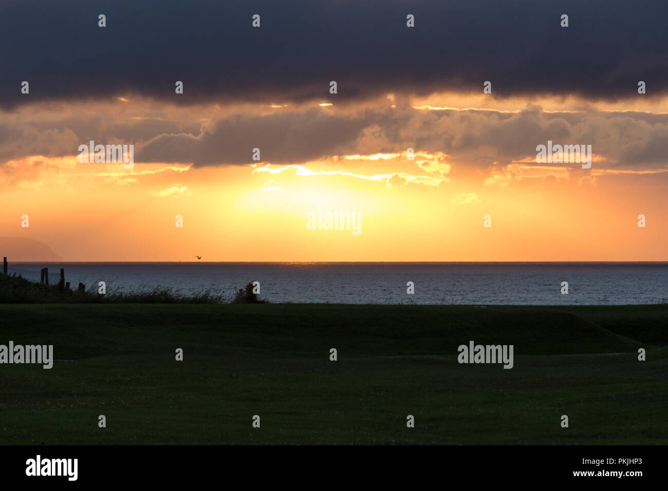 Drammatico tramonto arancione rottura attraverso le nuvole scure su costa North Antrim, Portstewart, N.Irlanda. Foto Stock