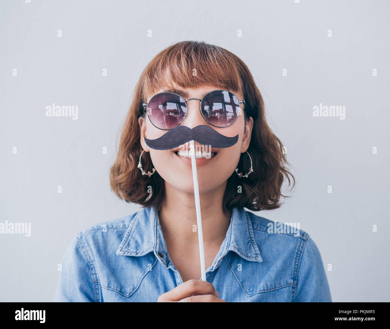 Bella donna asiatica di capelli corti jeans blu camicia e occhiali da sole  sorridente con baffi finti isolati su sfondo bianco Foto stock - Alamy