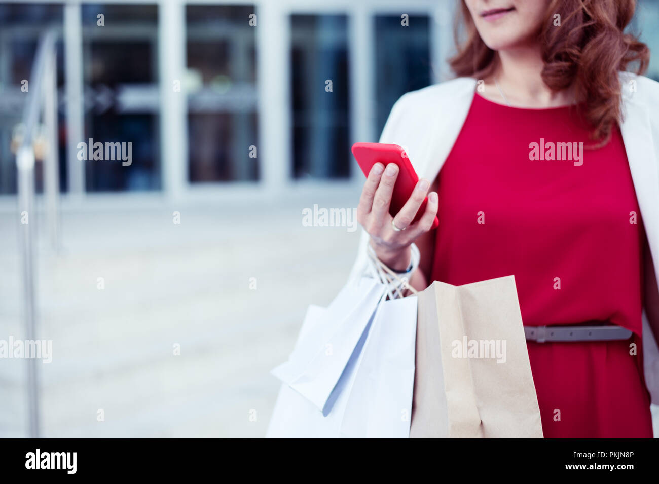 Shopper donna shopping a mano con uno smart phone e il trasporto del bagaglio Foto Stock