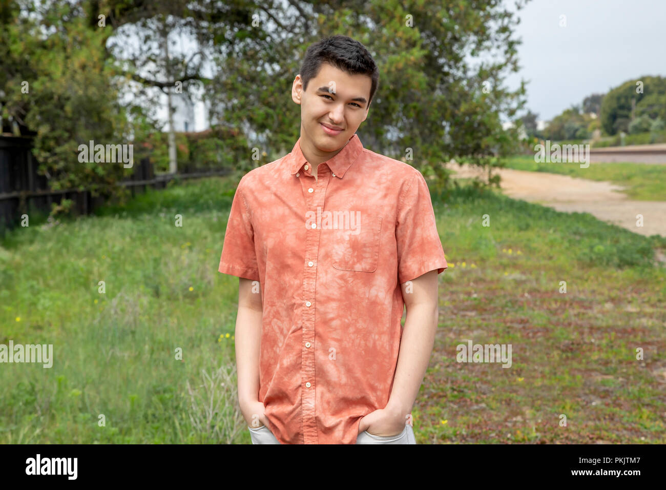 A 22 year old man standing all aperto con le mani in tasca, Carlsbad, California Foto Stock