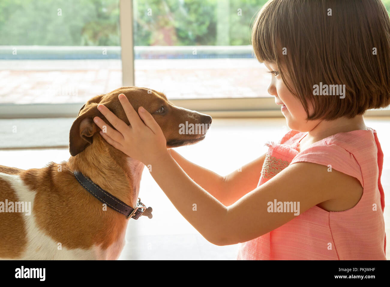Un bambino ragazza con il suo cucciolo la testa con le mani Foto Stock