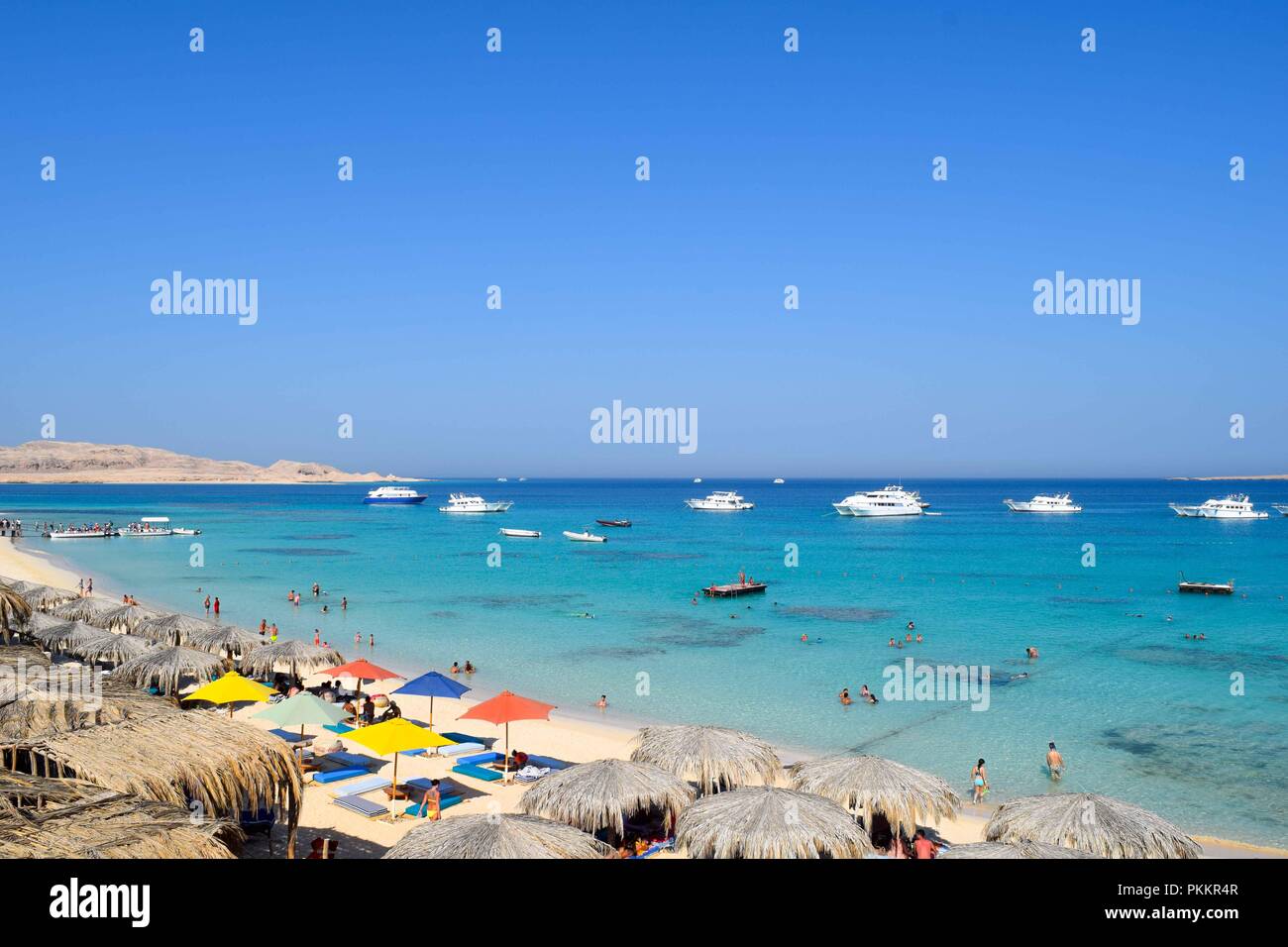 Vista su Mahmya isola, belle paradiso nel mare rosso, oceano turchese, ombrelloni presso la spiaggia di sabbia, cielo blu e alcuni turisti Foto Stock