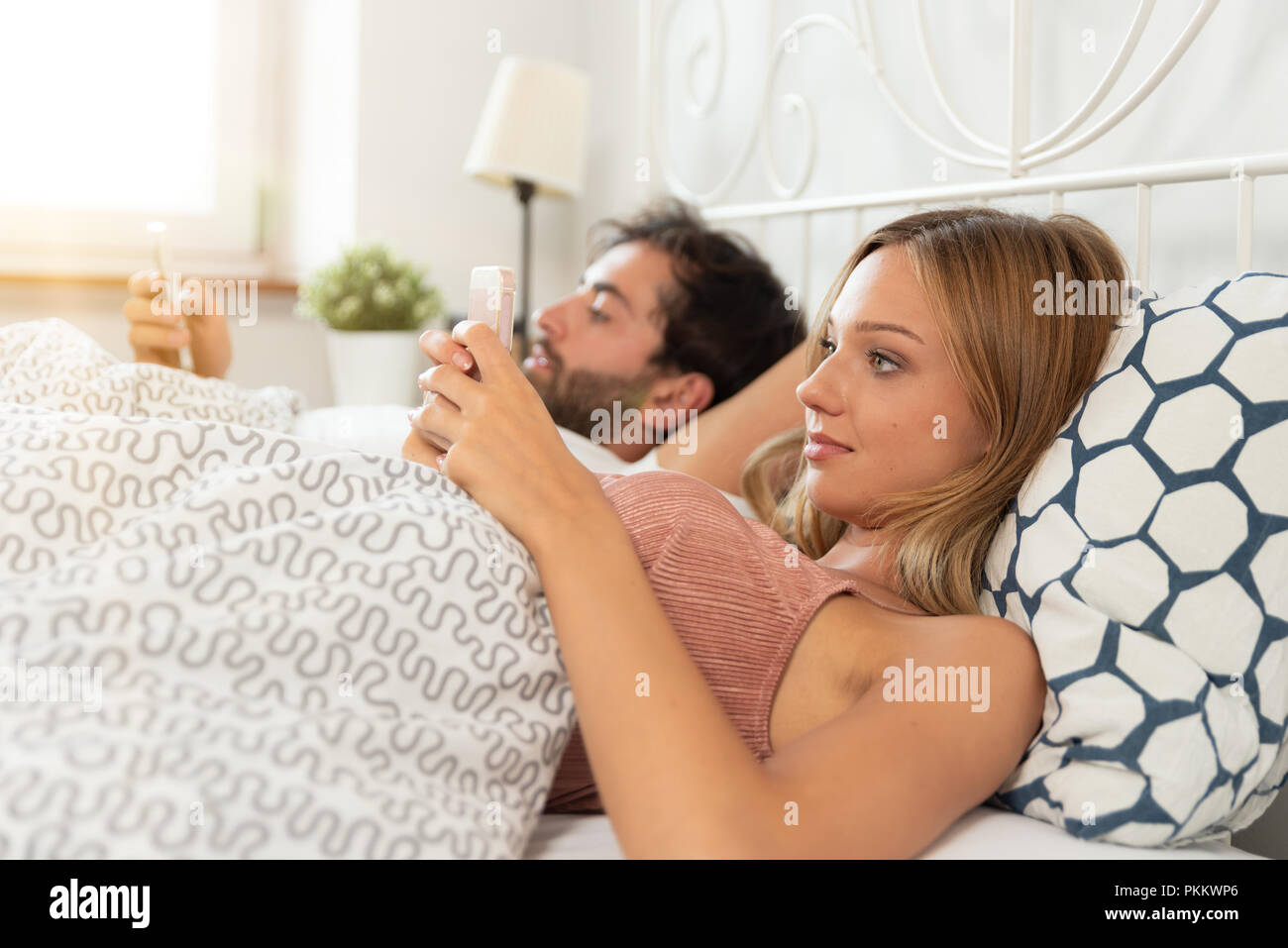 Coppia giovane con gli smartphone nel loro letto. Rapporto cattivo concetto Foto Stock