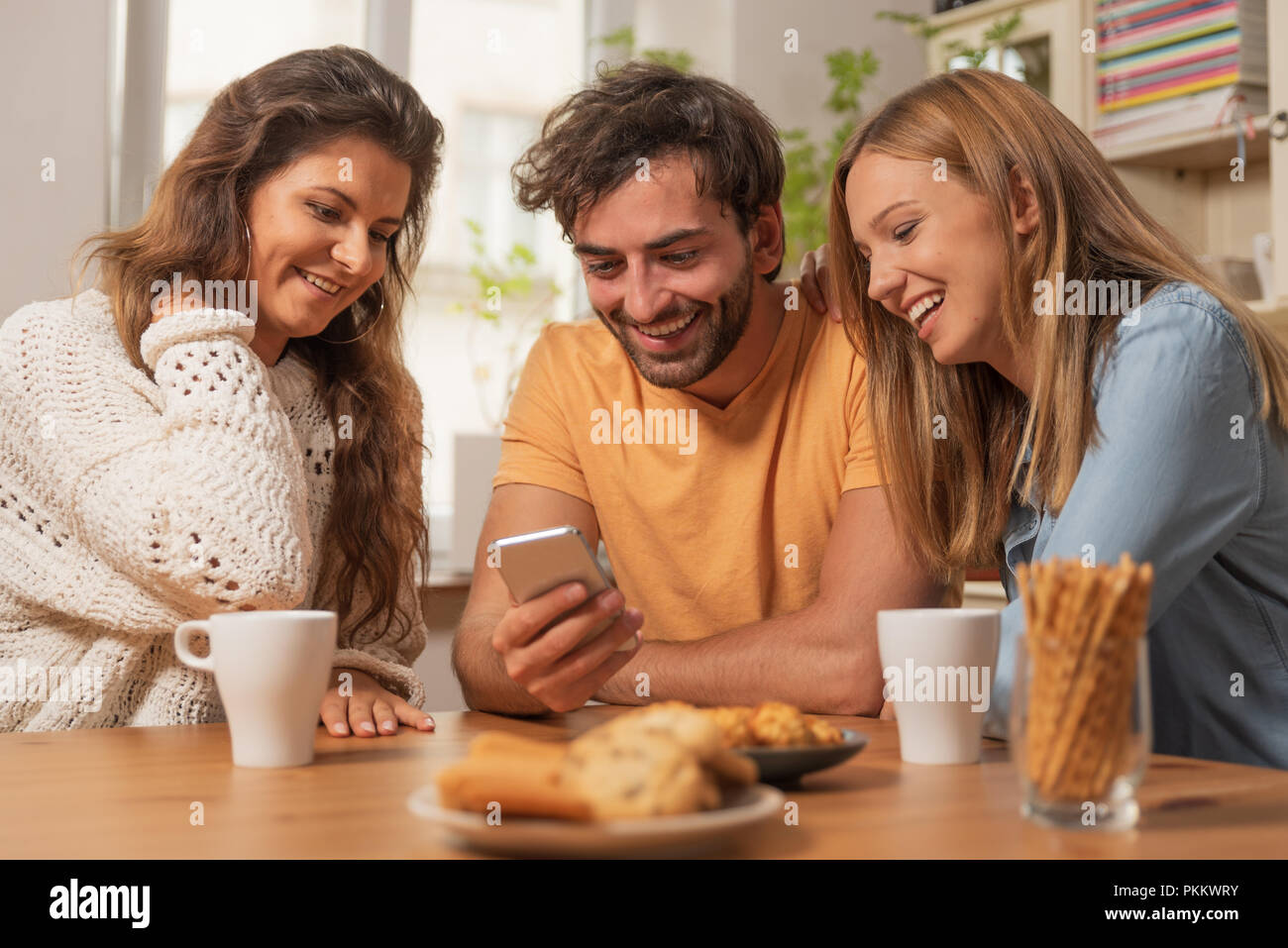 Gruppo di amici divertendosi con lo smartphone. Social media, tempo libero, la condivisione del contenuto, guardare divertenti video su internet. Foto Stock