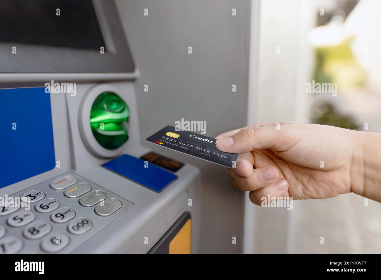 L'uomo mette mano carta di credito in ATM. Il denaro viene prelevato da un bancomat. Foto Stock