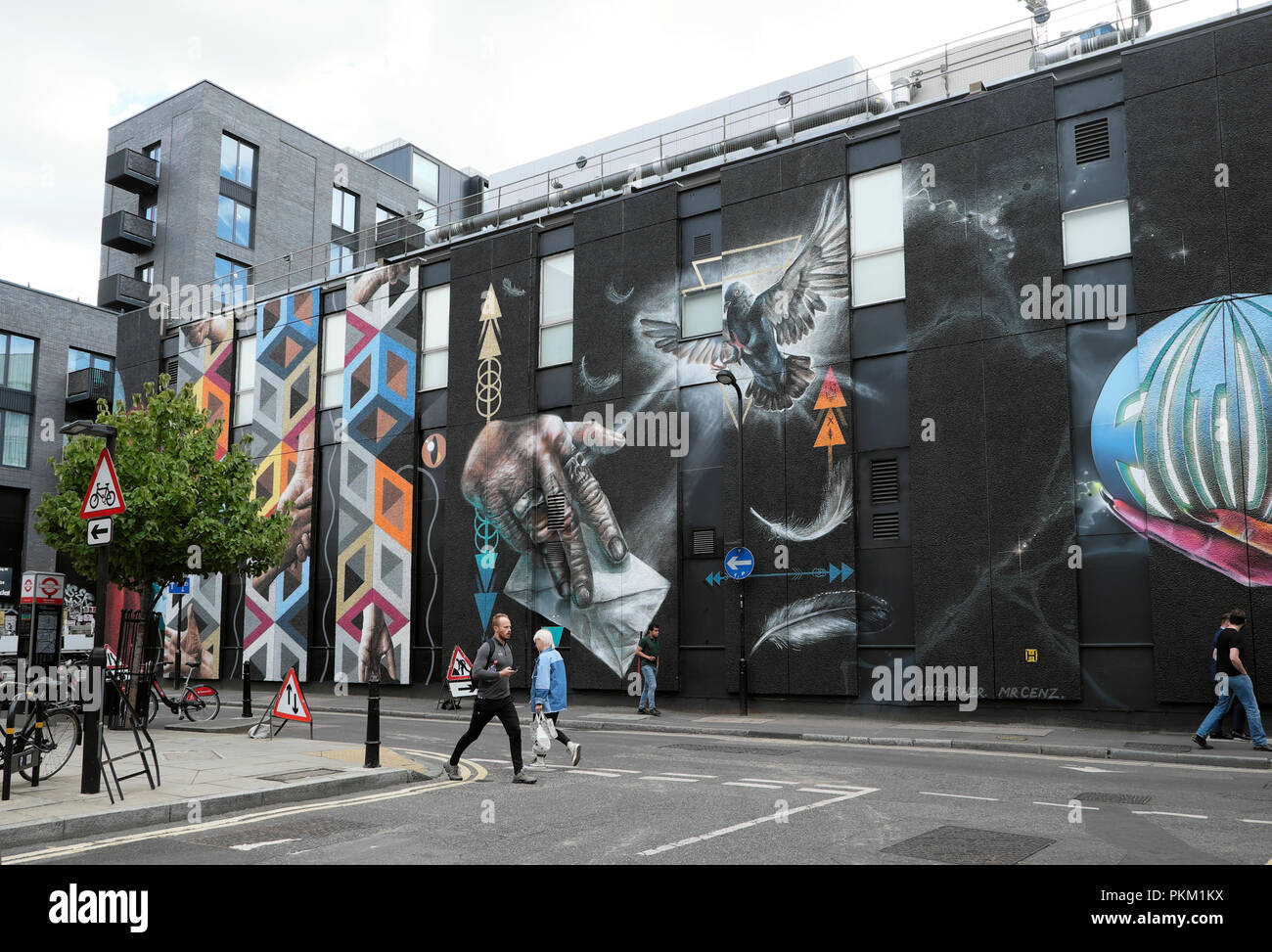 La gente camminare passato enorme street art pittura murale da molti artisti su una parete di un edificio in New Inn cantiere, Shoreditch Londra UK KATHY DEWITT Foto Stock