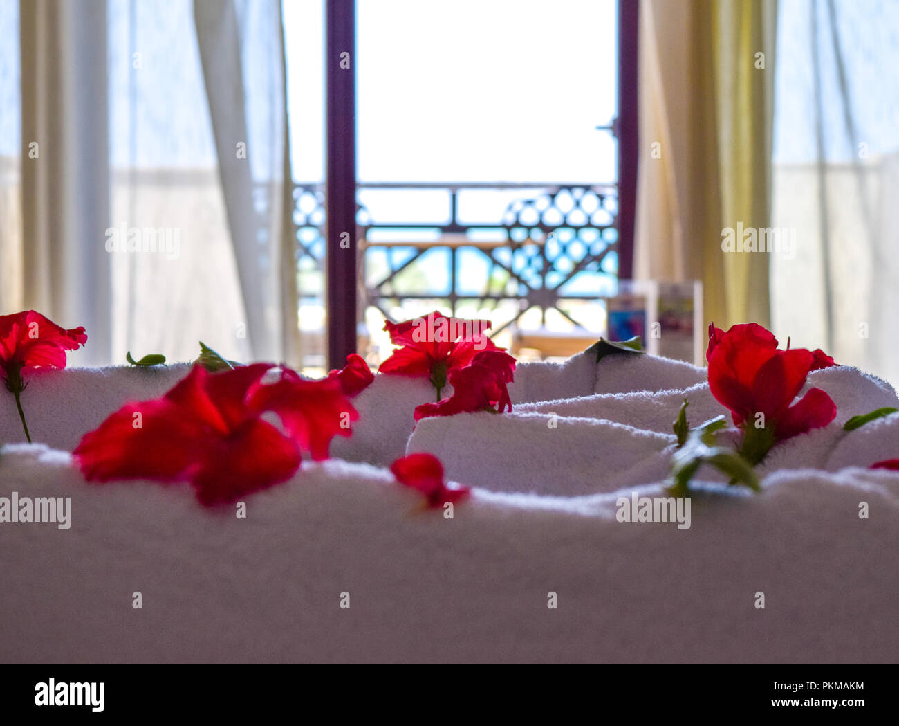 Ibisco petali di fiori sul letto con bella vista sul mare in background,  asciugamani bianchi decorazione circondato da petali di fiori di ibisco  Foto stock - Alamy