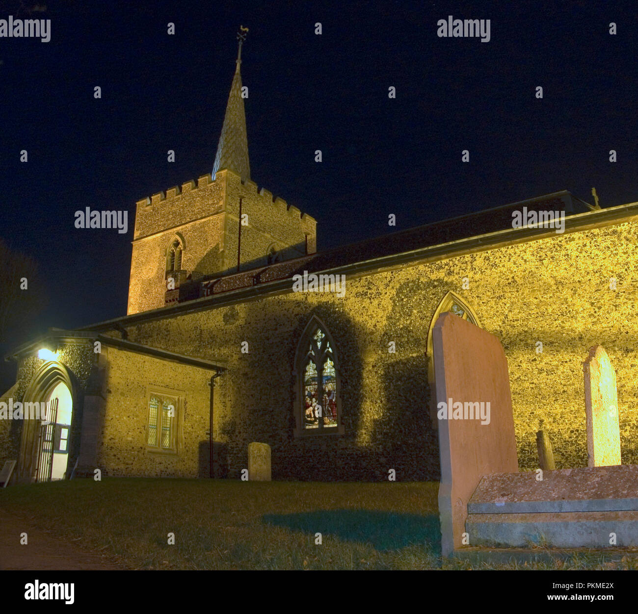 Grande chiesa di Santa Maria a Sawbridgeworth, Hertfordshire durante la notte mentre un servizio è in corso. sulla destra sono alcune tombe. Foto Stock