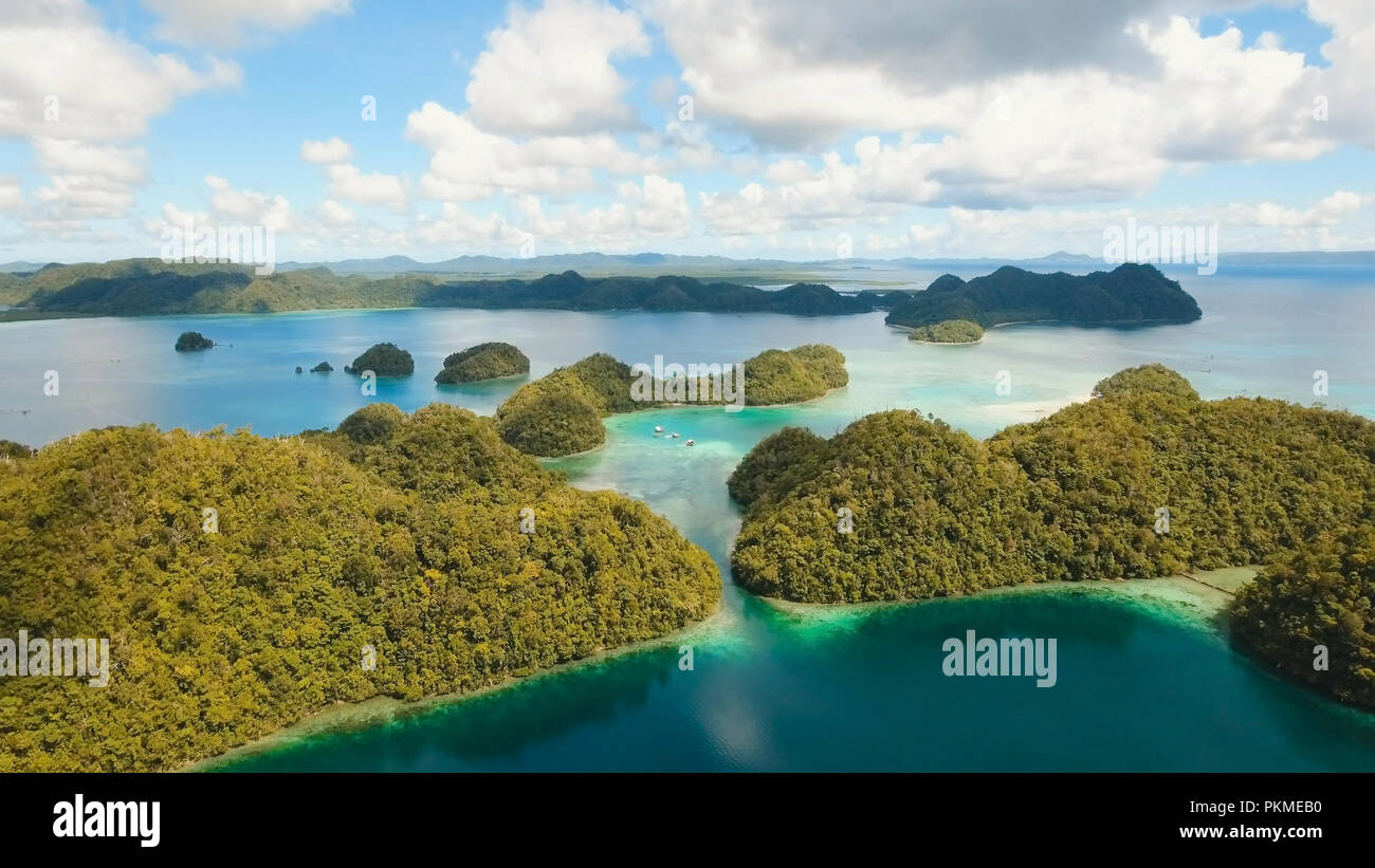 Vista aerea: spiaggia, isola tropicale, Baia Mare e laguna, Siargao. Paesaggio tropicale hill, nuvole e montagne rocce con la foresta pluviale. Acque azzurre della laguna. Paesaggio Shore Bay. Concetto di viaggio. Foto Stock