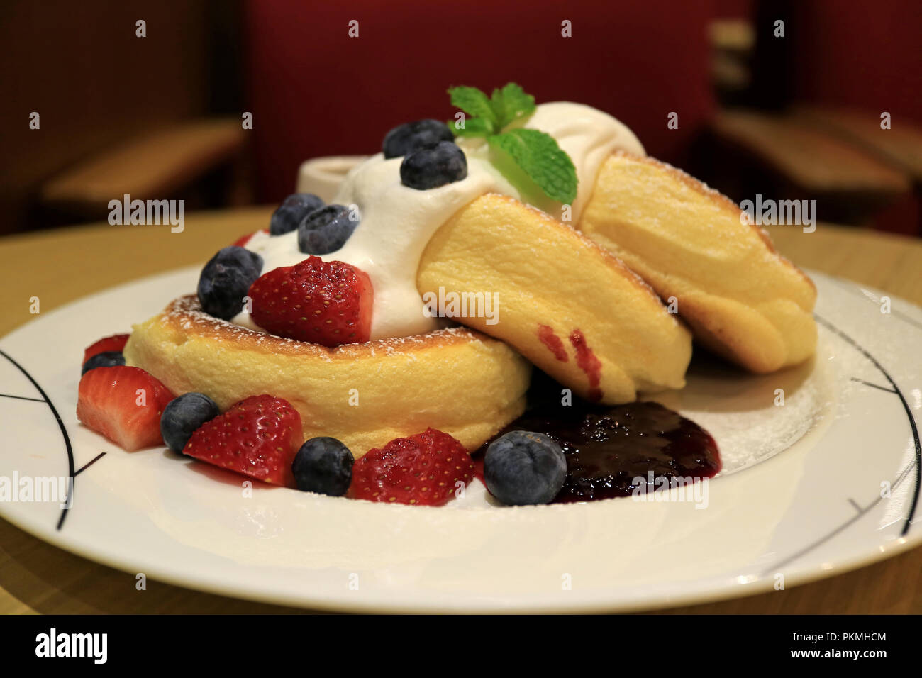 Acquolina in bocca Souffle soffici Pancake con panna montata e mescolare bacche servita su piastra bianca Foto Stock