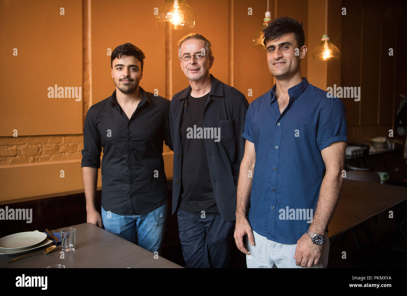 07 settembre 2018, Berlino: 07 settembre 2018, Germania Berlino: Andreas Toelke (C), il proprietario del ristorante Kreuzberger Himmel, sorge accanto al Odah siriano Bashi e il Jamshid afghana Safi (R). Aperto nel 2018 nei locali della parrocchia cattolica di San Bonifatius, Kreuzberger Himmel è un progetto di "essere un Angelo e.V.' Association, che ha lavorato per l'integrazione di profughi dal 2015. Nel ristorante Musulmani, Cristiani, indù e gli ebrei di lavorare insieme e offrono cucina siriana. Foto: Soeren Stache/dpa Foto Stock