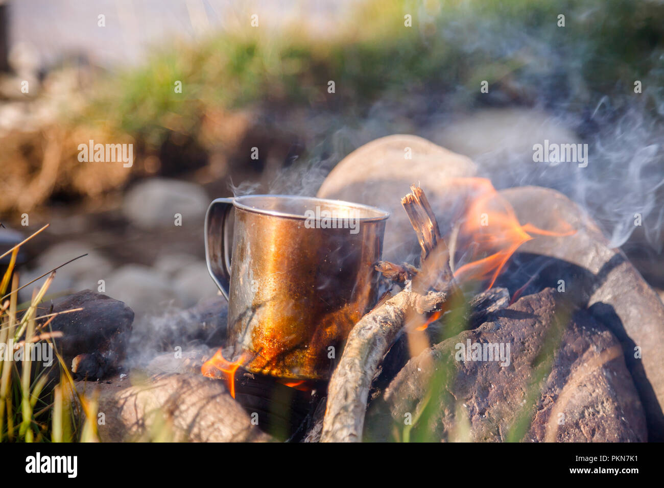 Warming tazza di tè o caffè sul fuoco ardente al campeggio selvaggio Foto  stock - Alamy