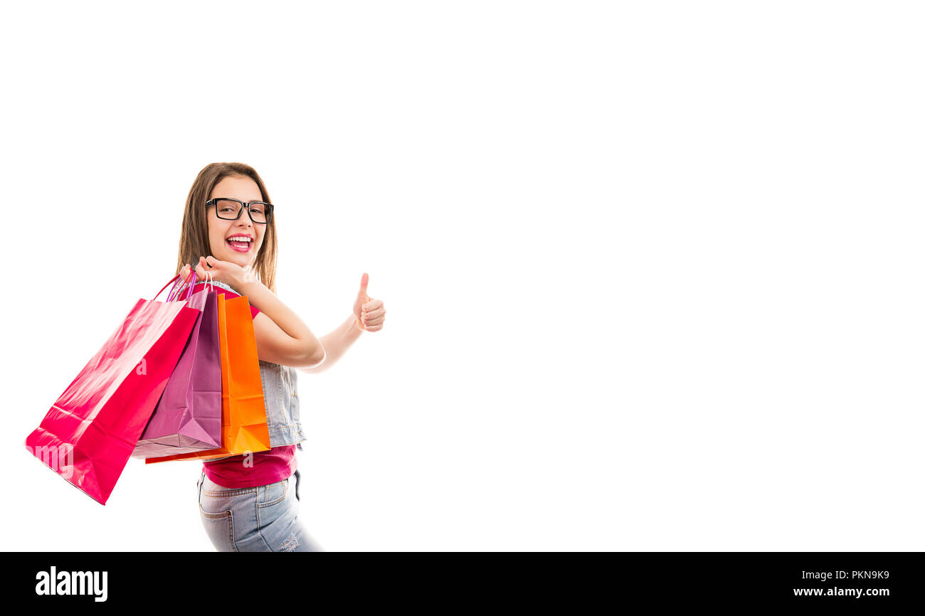 Vista laterale di eleganti donna felice in bicchieri con coloratissime shopping bags tenendo pollice in alto isolato su sfondo bianco Foto Stock