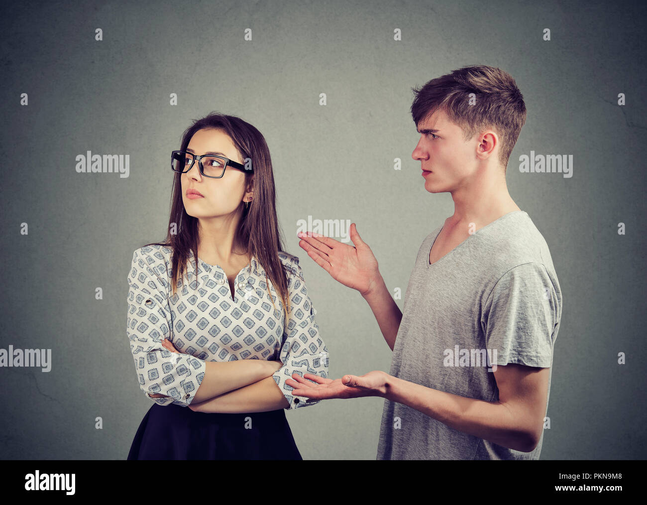 Giovane donna cercando offeso pur sostenendo con l uomo a fraintendere su sfondo grigio Foto Stock