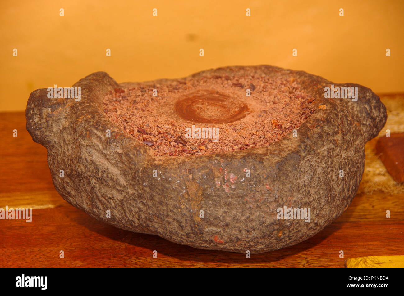 Close up di chicchi di cacao macinato in un mortaio di pietra, in un tavolo di legno sfondo Foto Stock