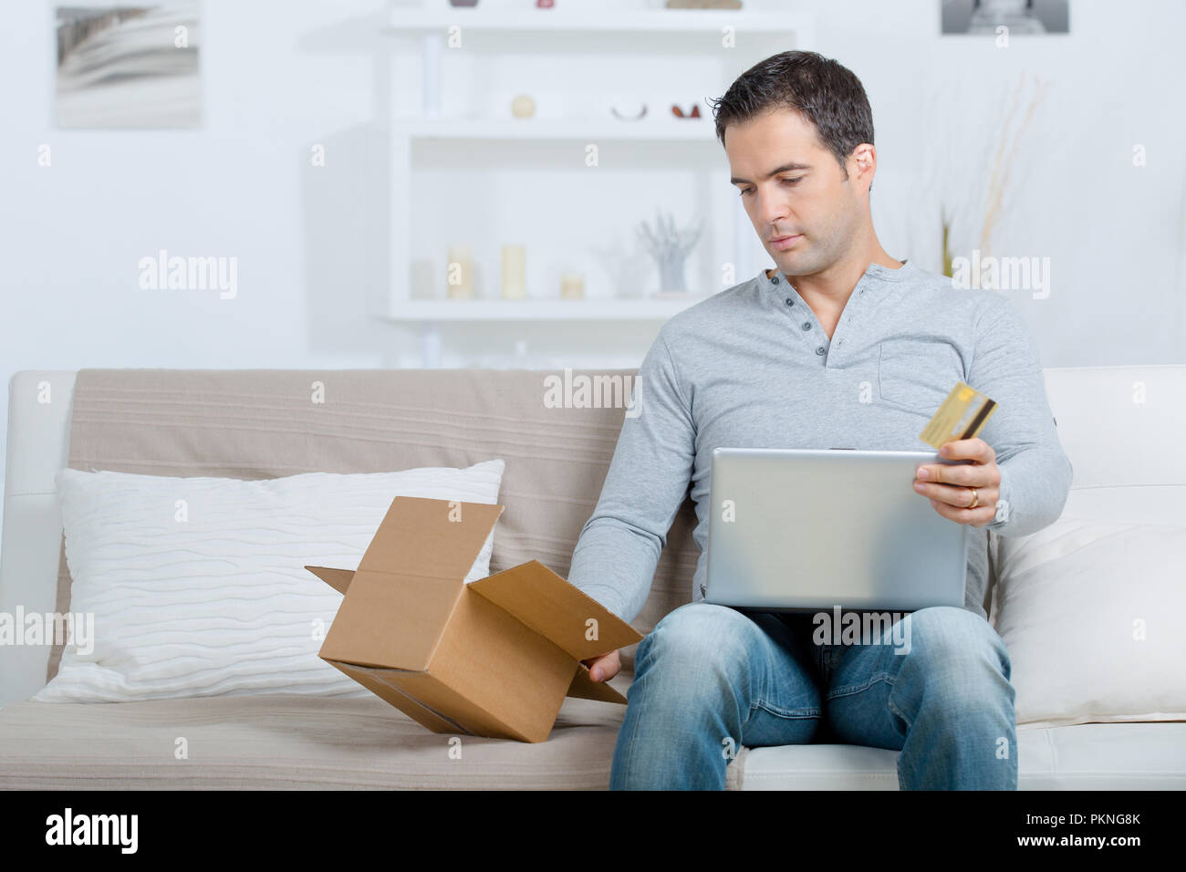 Uomo con carta di credito e computer laptop con box acquisti Foto Stock