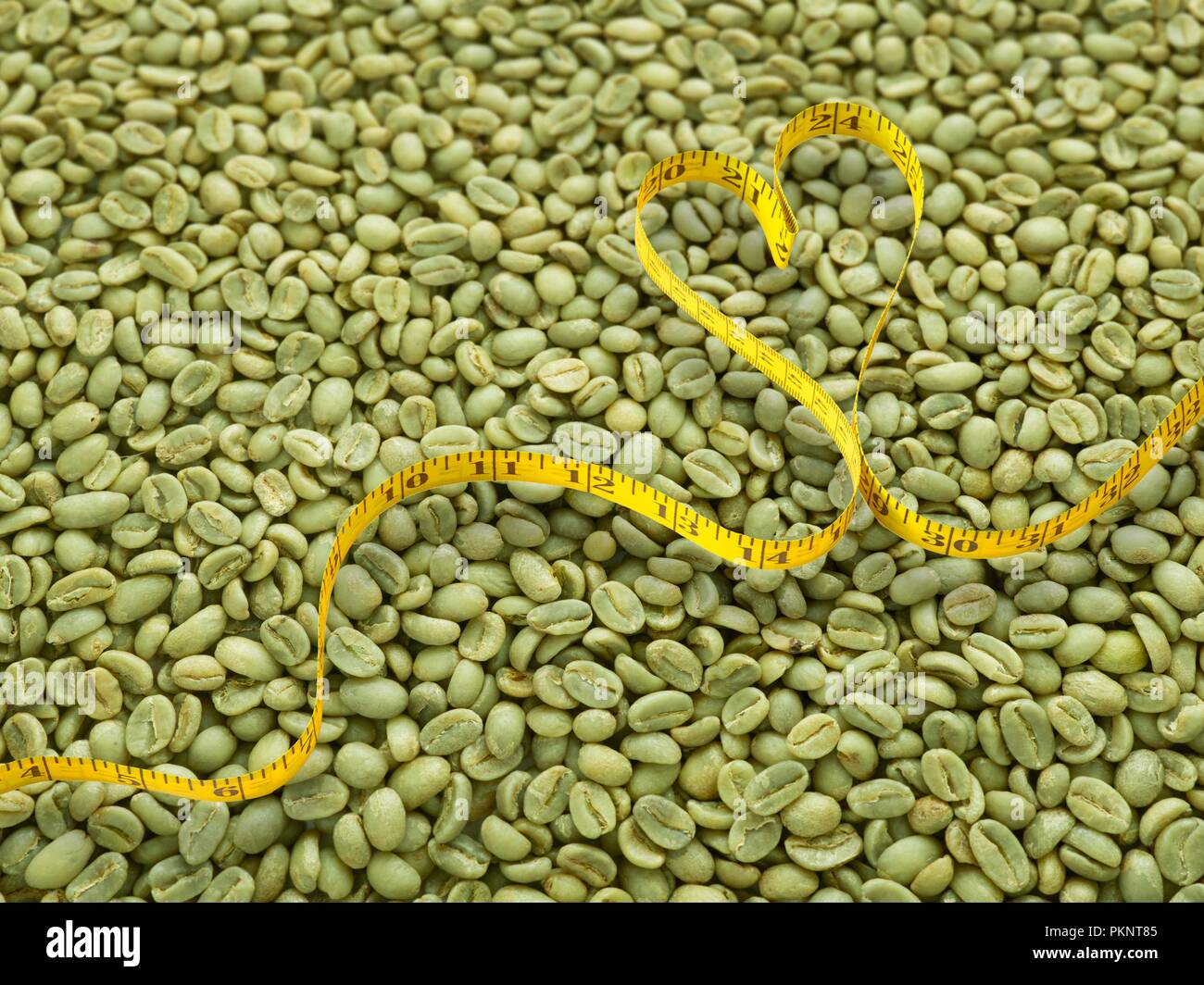 Chicchi verdi di caffè e forma di cuore nastro di misurazione. Foto Stock