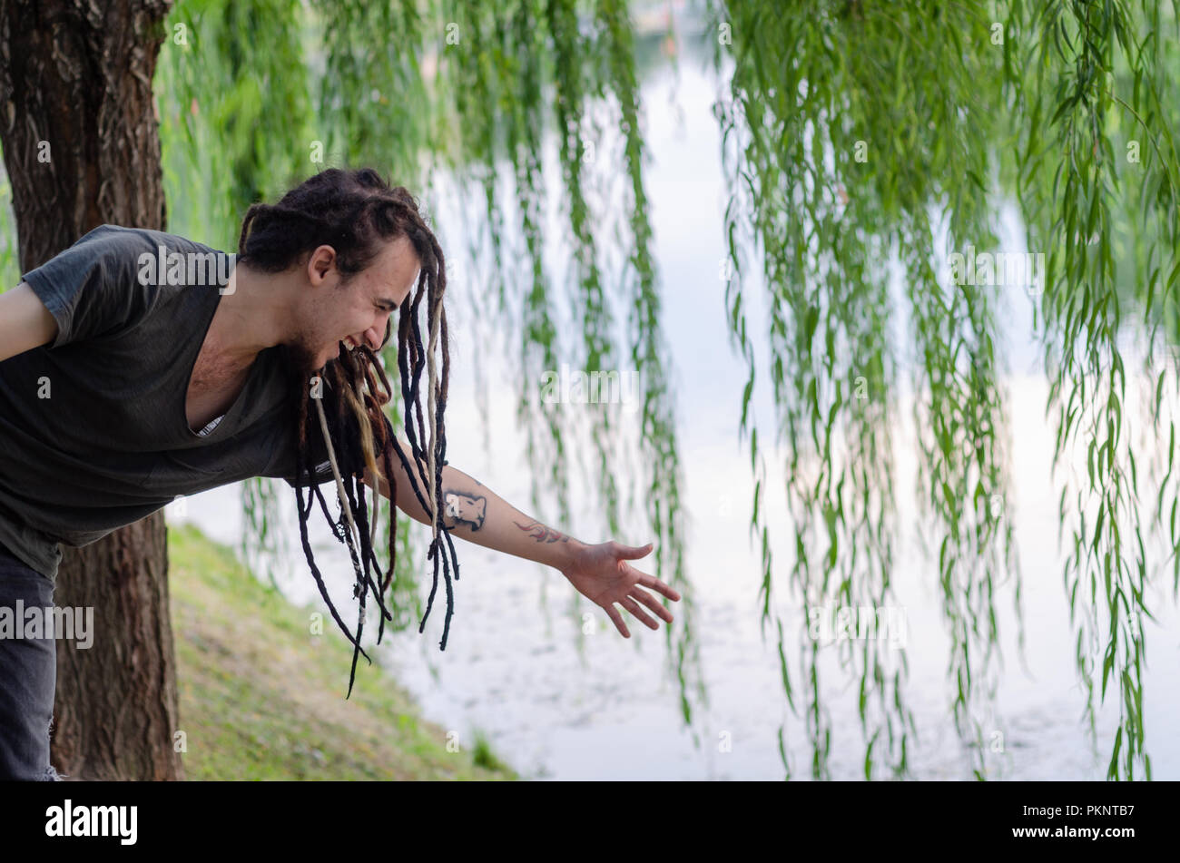 Il giovane uomo si estende la sua mano sul fiume e risate, Foto Stock