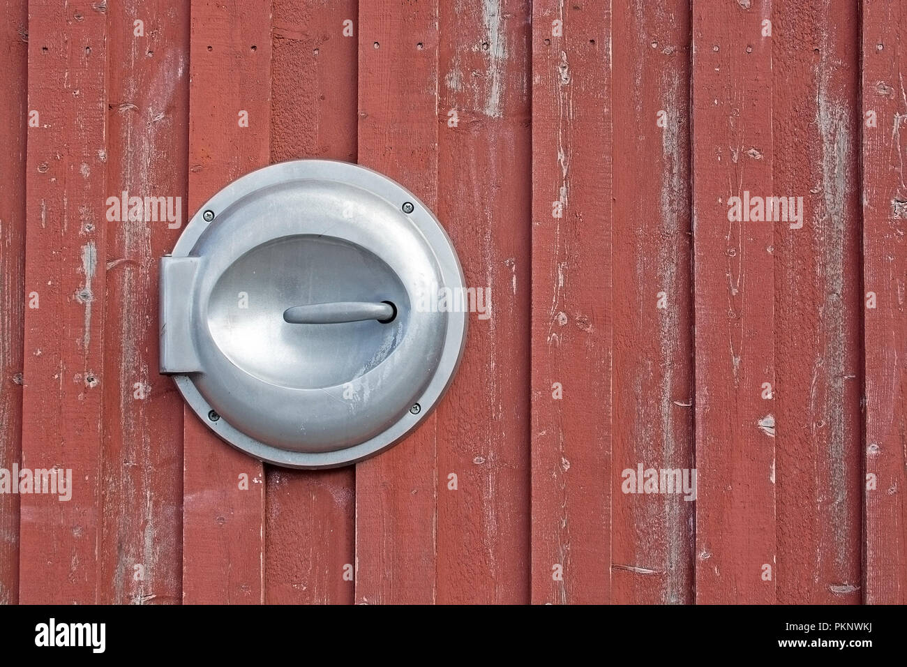 Coperchio in metallo per buttare immondizia su uno sfondo di legno verniciato in rosso Falu colore vernice tradizionale in Svezia Foto Stock
