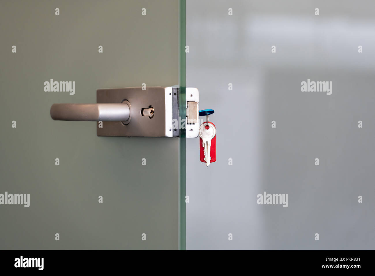 Moderna porta in vetro con lega di metallo maniglie e catena di chiave nella serratura, a casa o in ufficio il concetto di sicurezza Foto Stock