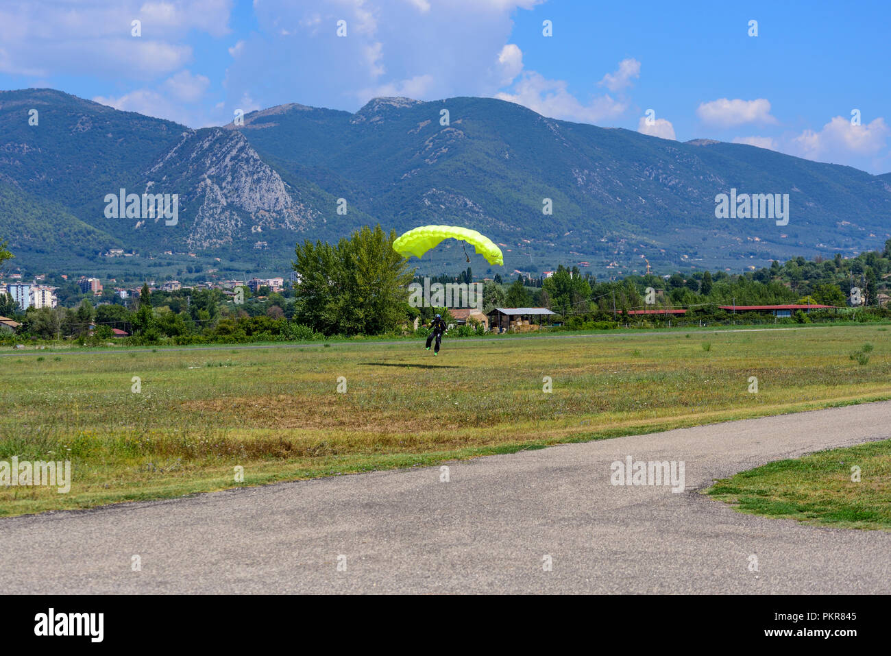 Parachutist con paracadute gialli atterra sul campo di volo Foto Stock