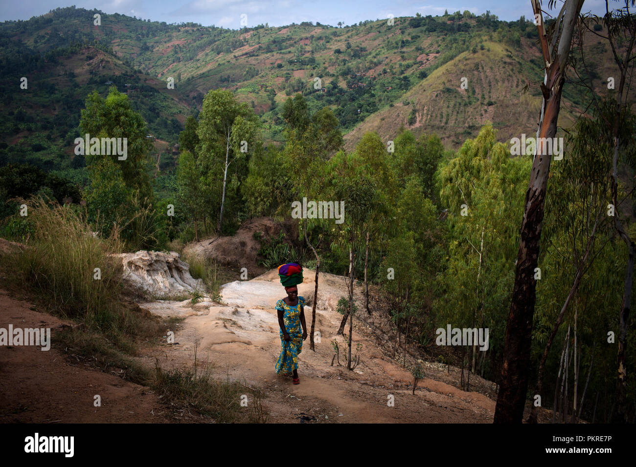 Una donna cammina fino alla cima di una collina che trasportano gli effetti personali al di fuori della capitale Bujumbura in Burundi il 31 maggio 2015. Foto Stock
