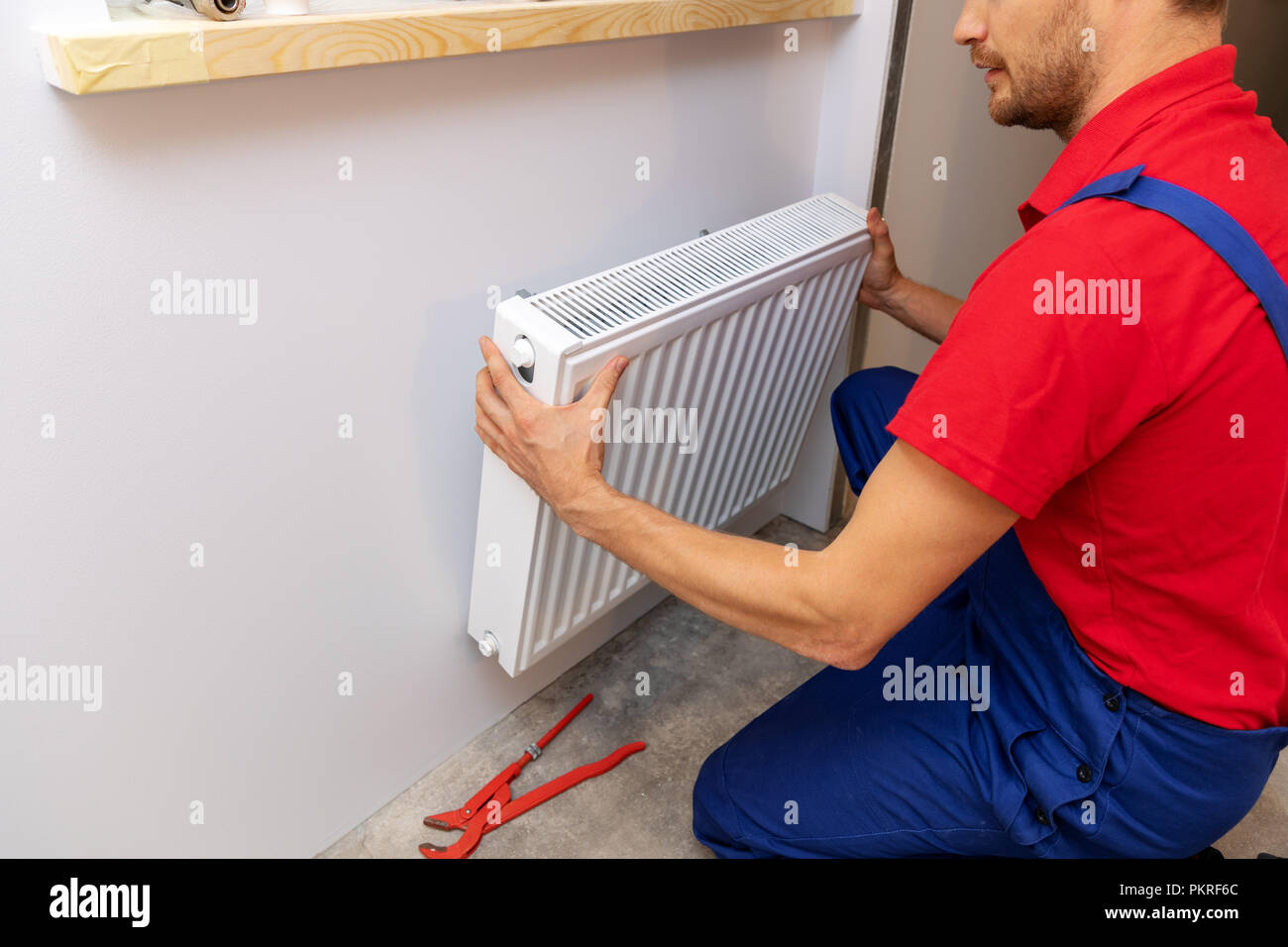 Servizi idrotermosanitari - idraulico installazione del radiatore di riscaldamento sulla parete Foto Stock