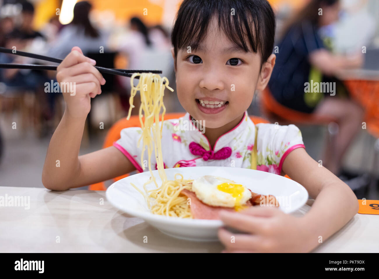 Cinese asiatici bambina mangiare tagliatelle con bacchette in ristorante  Foto stock - Alamy