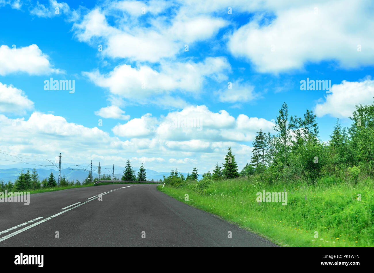 Strada asfaltata nel bosco. Il cielo è visibile. Foto Stock