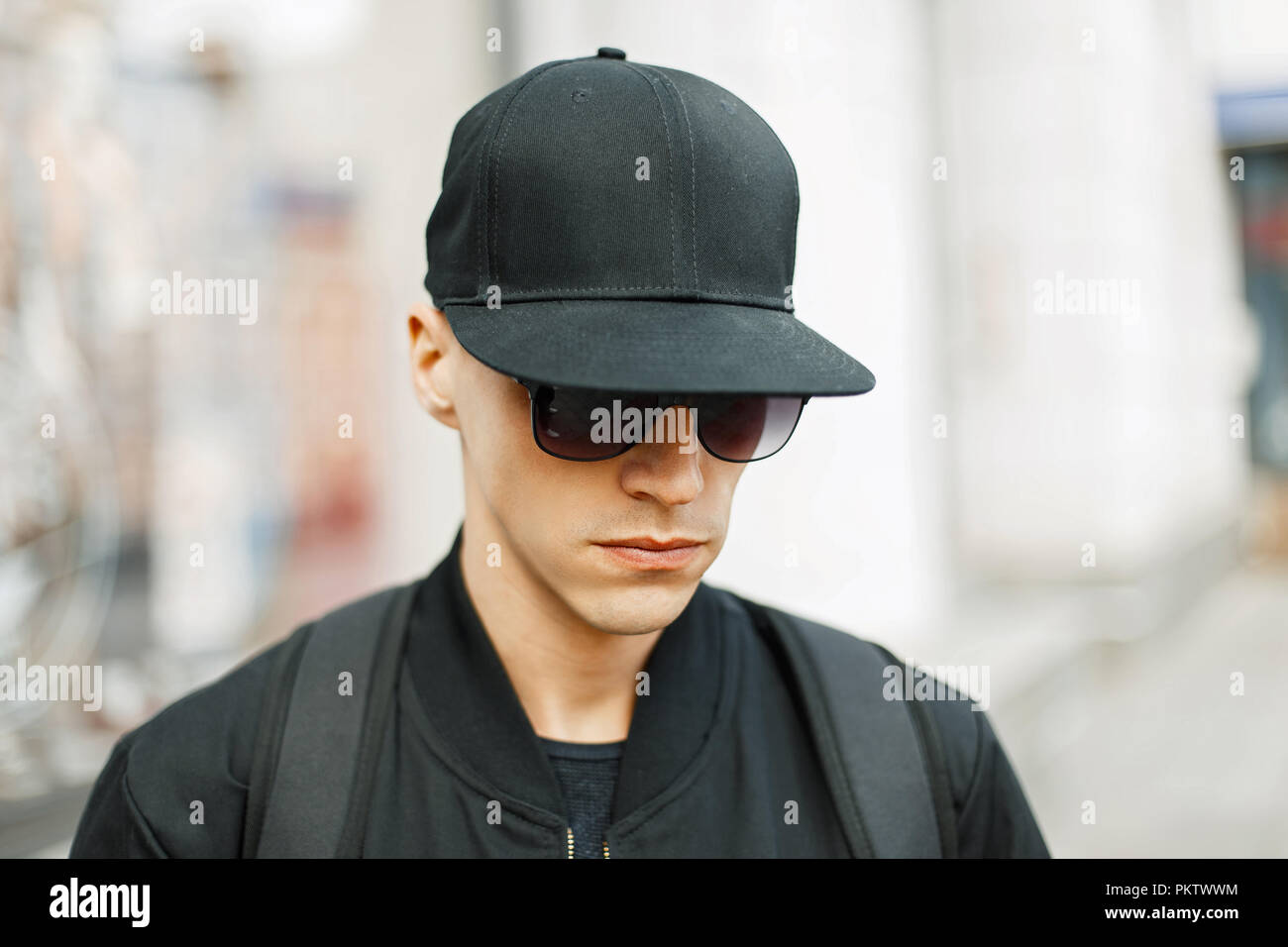 Bel ragazzo in un nero cappello da baseball e nero elegante abiti,  all'aperto Foto stock - Alamy