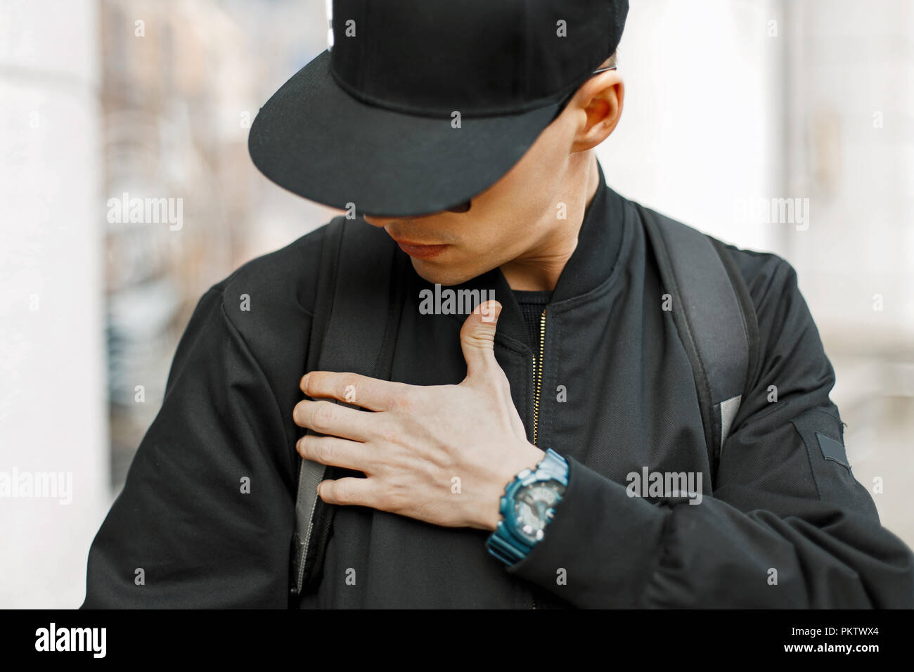 Moda uomo in un nero cappello da baseball e giacca nera in città Foto Stock
