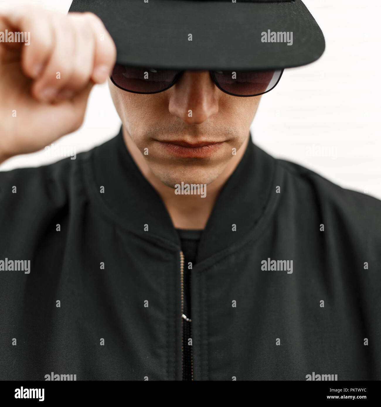 Elegante giovane uomo in occhiali da sole e un cappello nero Foto Stock