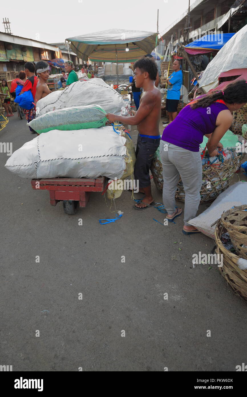 Cebu, Philippines-October 18, 2016: i fornitori di filippini caricare sacchi su un carrello nel mercato del carbonio più antico e il più grande mercato agricolo in città-denominato per TH Foto Stock