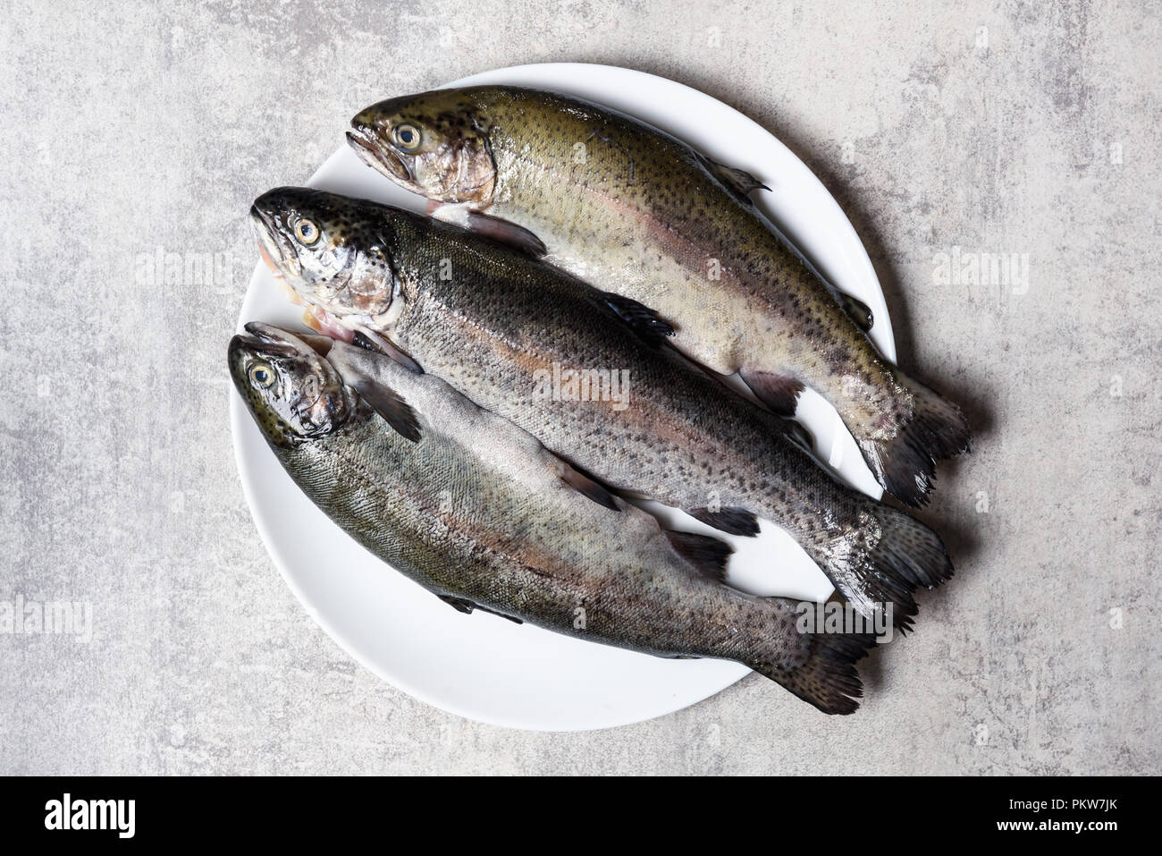 Tre trote pesce sulla piastra bianca Foto Stock