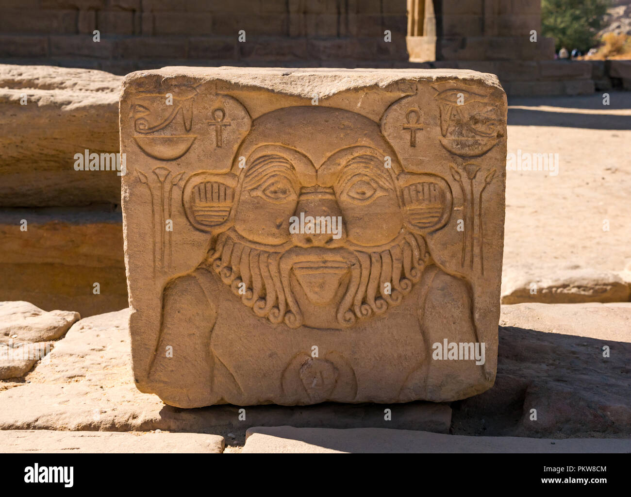 Insolito sculture su pietra del viso maschile con barba ricci su pietra e il Tempio di Philae, Fiume Nilo, Aswan, Egitto, Africa Foto Stock