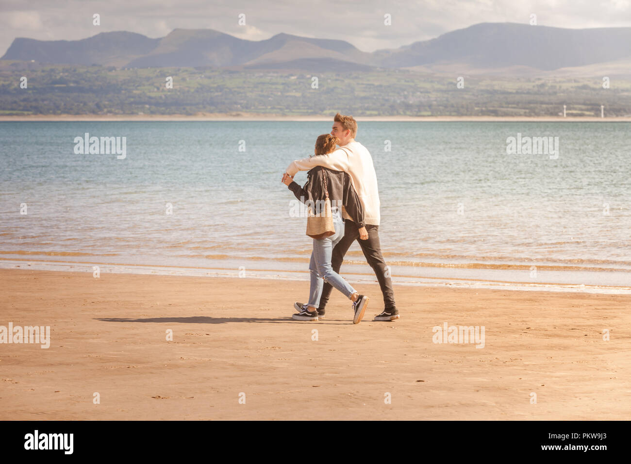 Due persone che camminano su una spiaggia tranquilla in estate, Anglesey, Galles REGNO UNITO Foto Stock