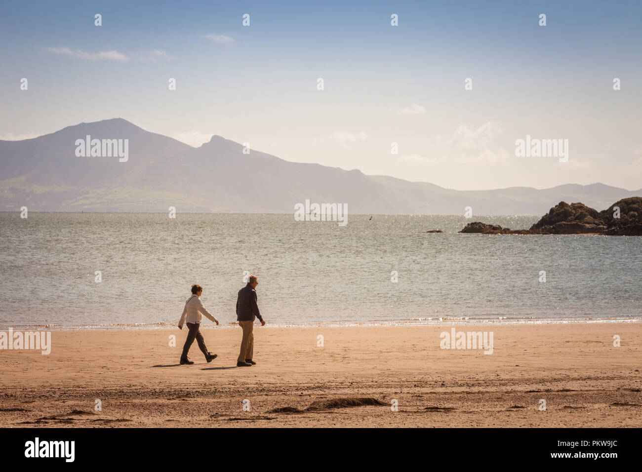 Due persone che camminano su una spiaggia tranquilla in estate, Anglesey, Galles REGNO UNITO Foto Stock