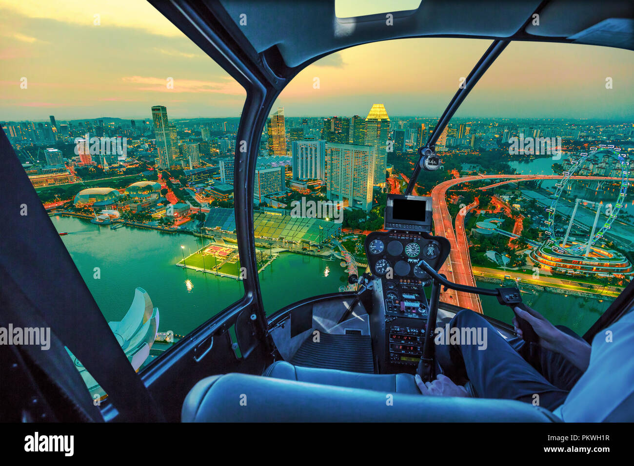 Volo panoramico in elicottero sopra Singapore twilight panorama all'alba. Notte urbana scena dell'antenna dall'interno della cabina con Singapore cityscape con la ruota panoramica Ferris al tramonto. Foto Stock