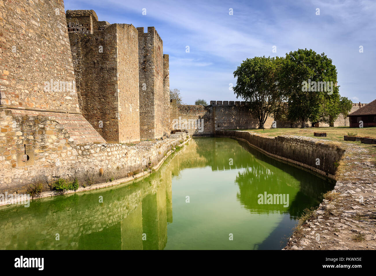 Sorprendente antica fortezza Smederevo muri in pietra la riflessione nel canale con acqua verde Foto Stock