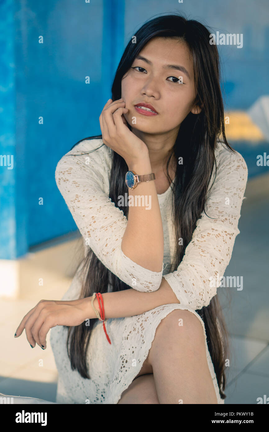 Ragazza in posa per la telecamera mentre seduto contro uno sfondo blu. Foto Stock
