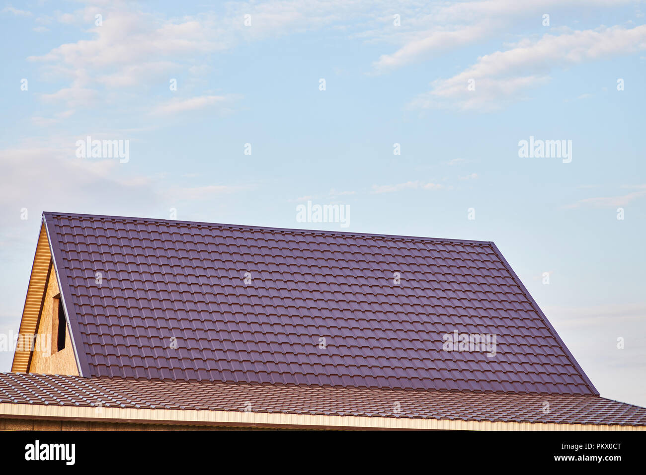 Il tetto della casa è coperto con la Borgogna Piastrella in metallo Foto Stock