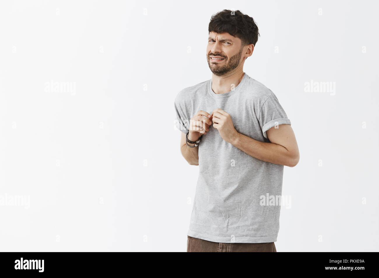 Orinato divertenti e childigh maschio europeo con elegante scuro i capelli e barba scendere e accigliata da disgusto e avversione premendo le mani al petto, esprimendo antipatia e dispiacere Foto Stock